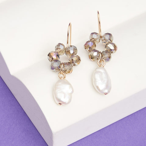 Dangling earrings with silver glass beads arranging in a flower shape with a pearl hanging from it.