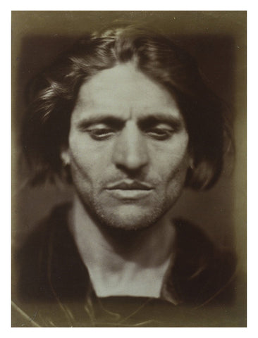 Photographic postcard of a man with long hair looking down.
