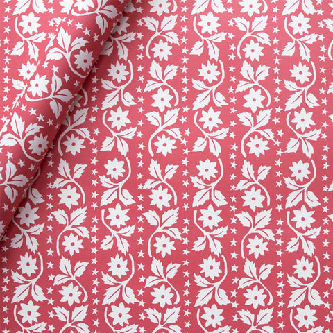 Red wrapping paper with white flowers and stars in a linear fashion. 