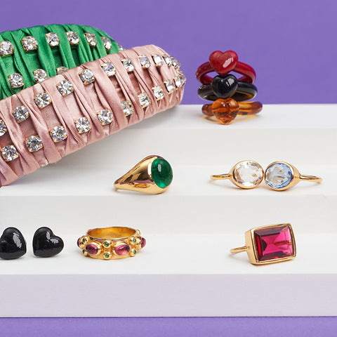 A collection of gold and gem rings displayed on a small white staircase.