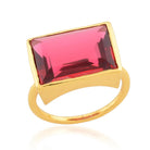 A gold band ring with a rectangular ruby red crystal in the centre.