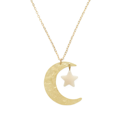 A large brass crescent moon pendant with small white star hang from a gold chain.