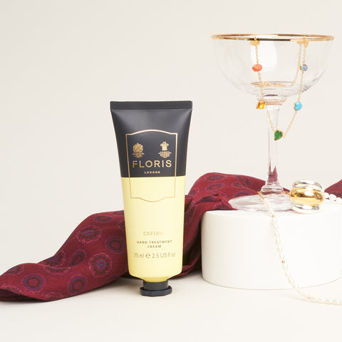 The burgundy bandana wrapped around some hand cream and next to a cocktail glass.