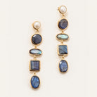 A pair of gold drop earrings featuring a white pearl at the top, followed by multiple blue labradorite stones in oval, round, and square settings, displayed on a clean off-white background.