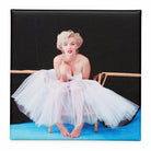 Fridge magnet with a vintage-style image of a woman in a white dress sitting on a blue platform.