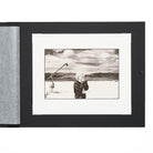 Open folio with black cover and a black and white photograph of a woman with a microphone against a landscape.