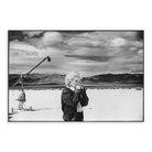 Black and white photograph of a person with a microphone against a scenic background