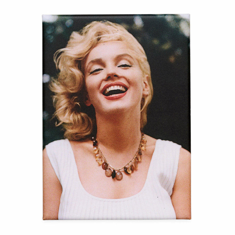 Fridge magnet with a portrait of a woman laughing and wearing a necklace against a dark background