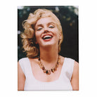 Fridge magnet with a portrait of a woman laughing and wearing a necklace against a dark background