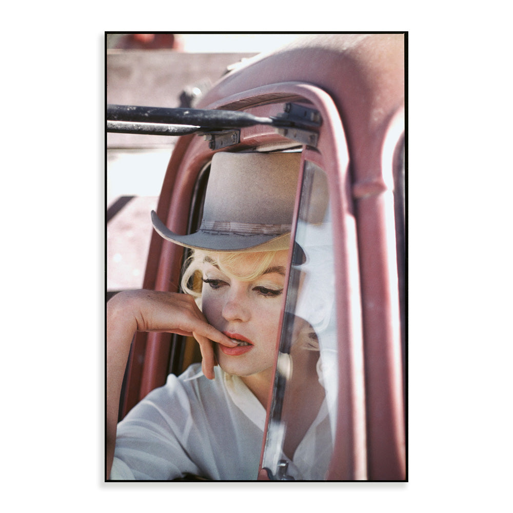 Colour photograph of a person wearing a hat, looking out of a pink vehicle window
