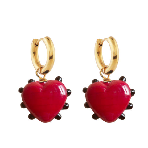A pair of red glass heart pendants with outer black dot detailing hanging from gold hoops.