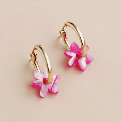 A pair of gold hoop earrings with a pink flower charm hanging from each hoop.