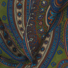 Close-up of a patterned fabric with intricate designs in green, blue, and brown.