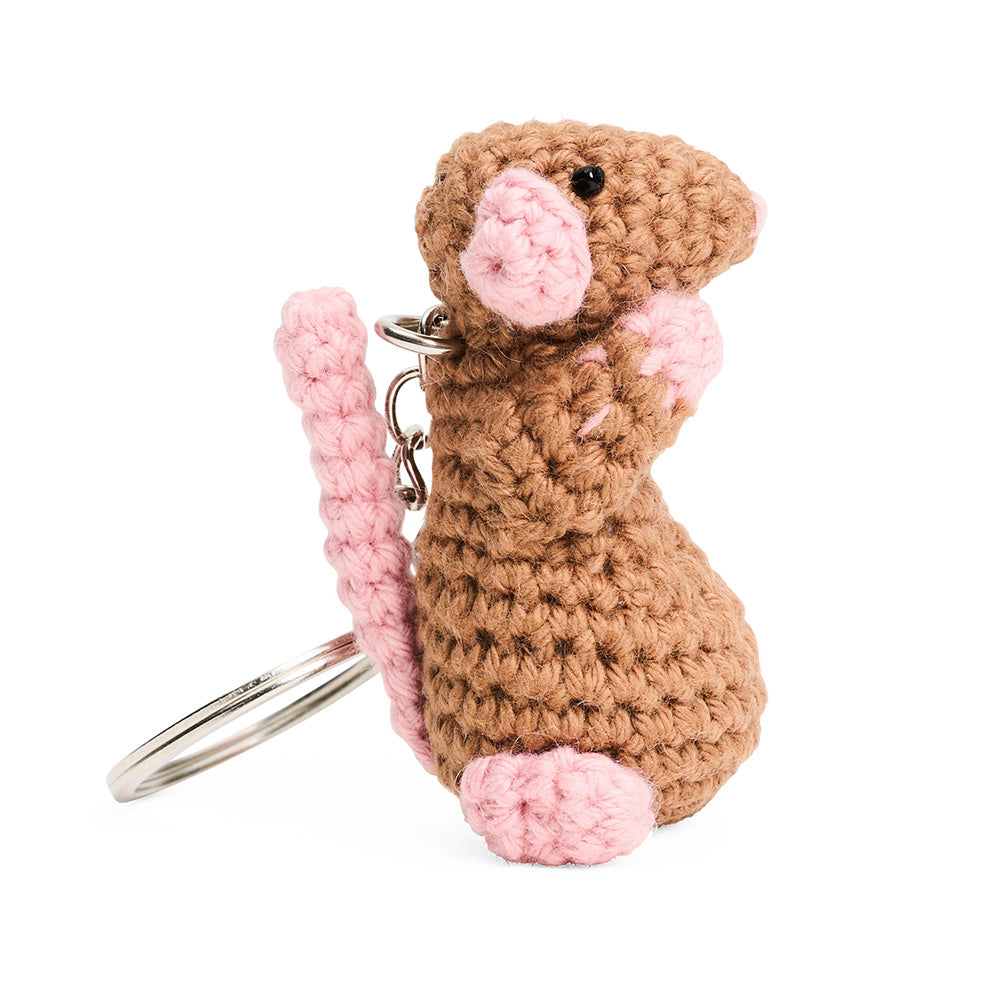 Side view of crocheted mouse keychain with pink tail and black beaded eyes on a white background