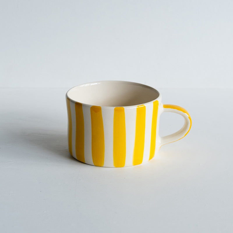 Wide ceramic mug with handle and painted yellow vertical stripes. 