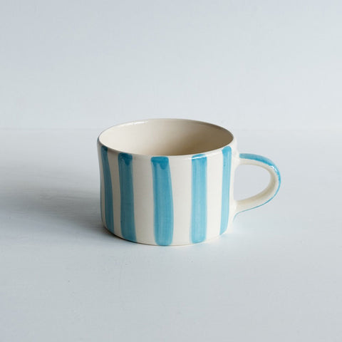 Wide ceramic mug with handle and painted turquoise vertical stripes.