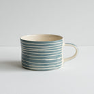 A single mug with white striped design against grey.