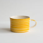 A single mug with handle and a scratched white stripe design against yellow.