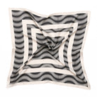 A styled monochrome square scarf with geometric white shapes and black swirls. 