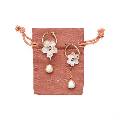 Small gold hoop earrings with an ivory flower charm with a dangling pearl below on its Wolf & Moon rust coloured packaging.