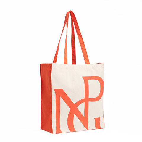 A large rectangular cream tote bag with red handles and sides and a red NPG monogram design.