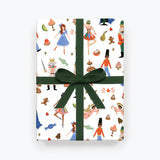 The white Nutcracker wrapping paper on a box with a dark green bow. 