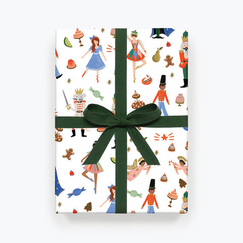 The white Nutcracker wrapping paper on a box with a dark green bow. 