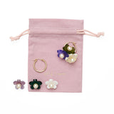 Disassembled hoop earring and flower charms against a pink drawstring bag.