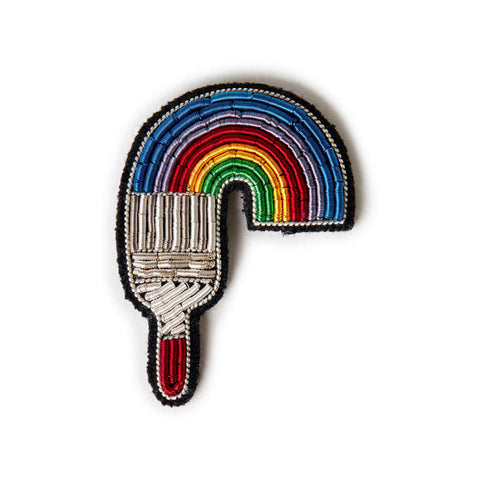 Embroidered brooch featuring a paint brush painting a rainbow.