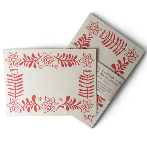 A blank white card with a red fern and flower border. 