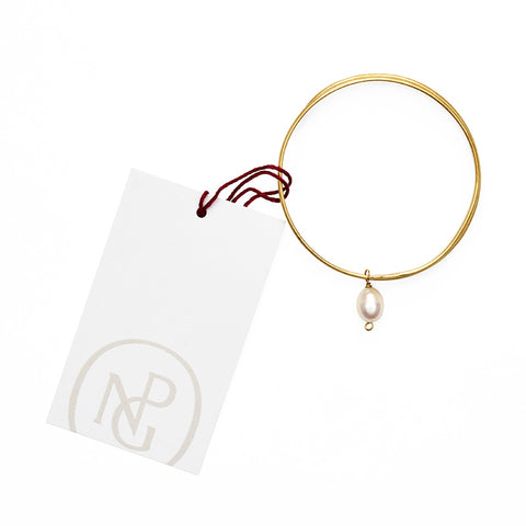 Gold bangle bracelet with a single hanging pearl pendant on NPG packaging.