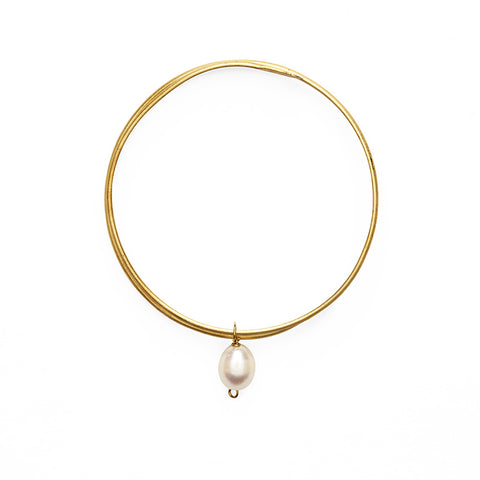 Gold bangle bracelet with a single hanging pearl pendant. 