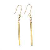 A pair of gold hoop earrings with a single pearl and gold bar hanging from each below. 