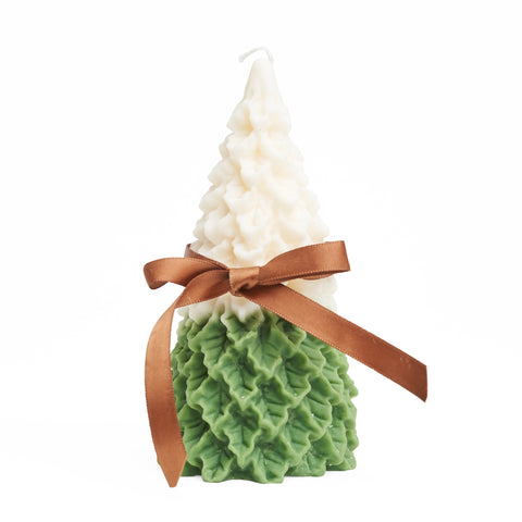 A snow covered pine tree candle with a small brown bow around it. 