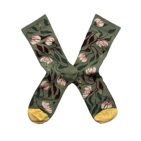 A pair of green socks with pink flowers design growing from a stem and yellow toes.