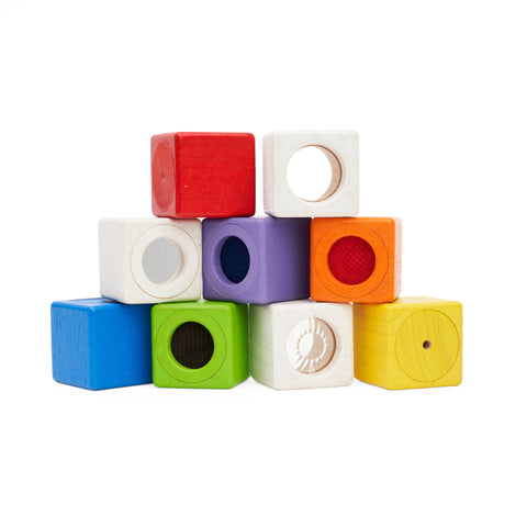 A pile of nine coloured wooden blocks each with a central circle of a textured material.