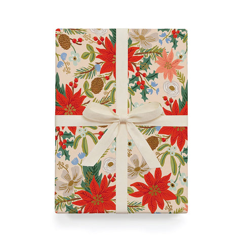 The red poinsettia wrapping paper on a present with a white bow. 