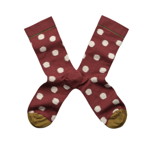 A pair of bugundy socks with white polka dots and green toes.