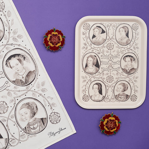 A tea towel and tray illustrated with the six wives of Henry VIII are displayed amongst textile Tudor rose decorations.