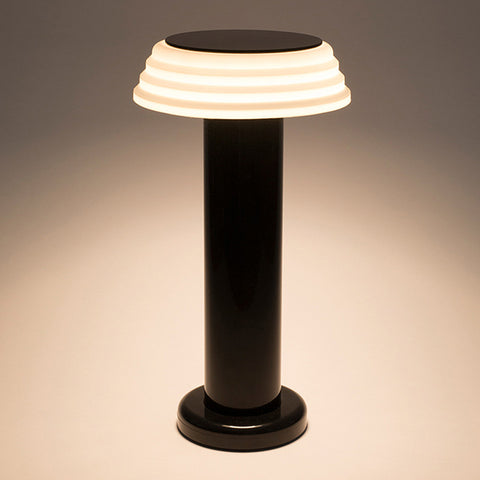 Portable black and white lamp with the light turned on.