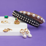 A collection of gold rings, earrings and pearl headbands rest on a miniature staircase against a purple backdrop.