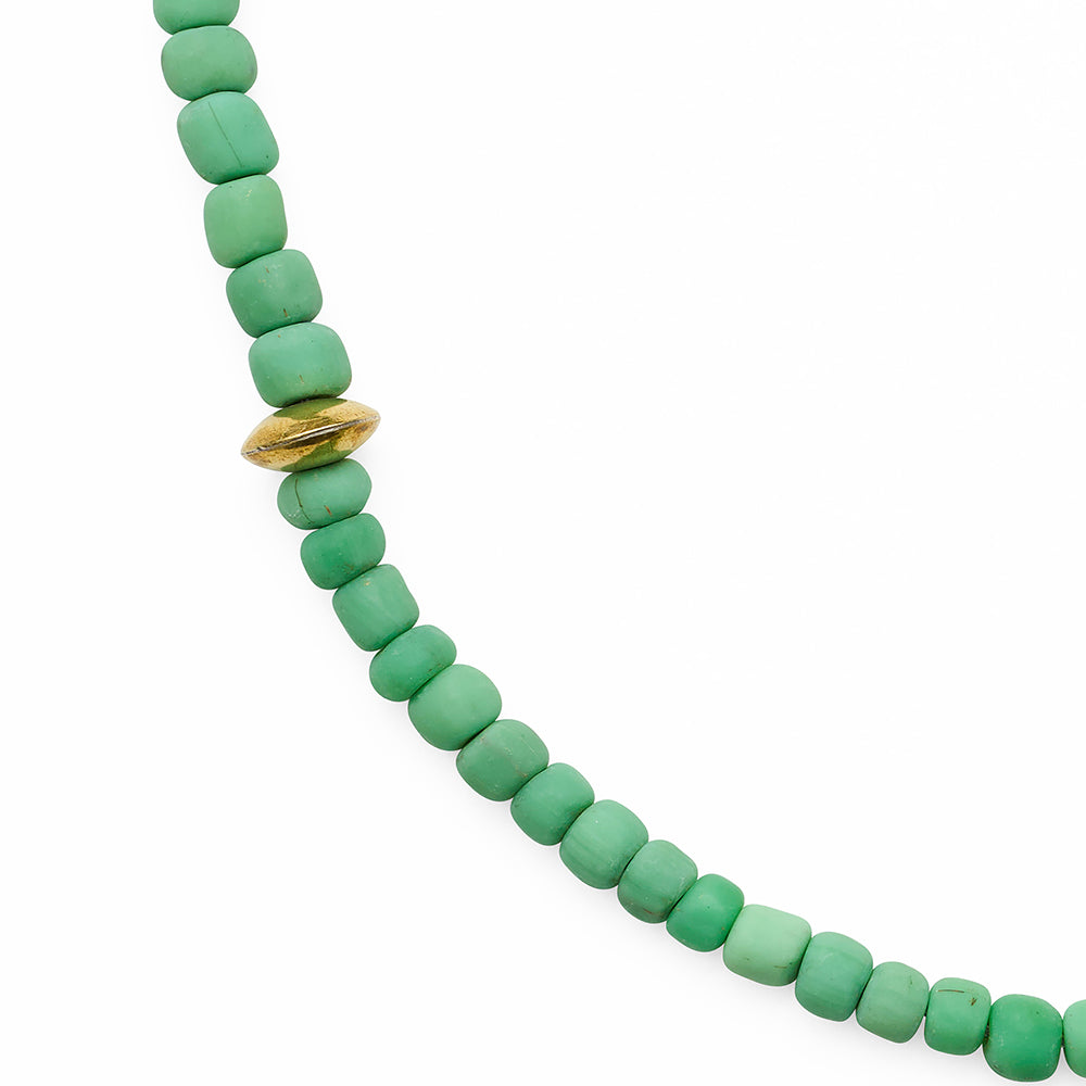 Green beaded necklace with a gold accent on a white background