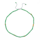 Green beaded necklace with gold accents on a white background