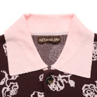 Close-up of a brown cardigan with a pink collar and brand label on a white background