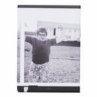 Magnet with a black and white photo of a child with arms raised, framed in a black border.