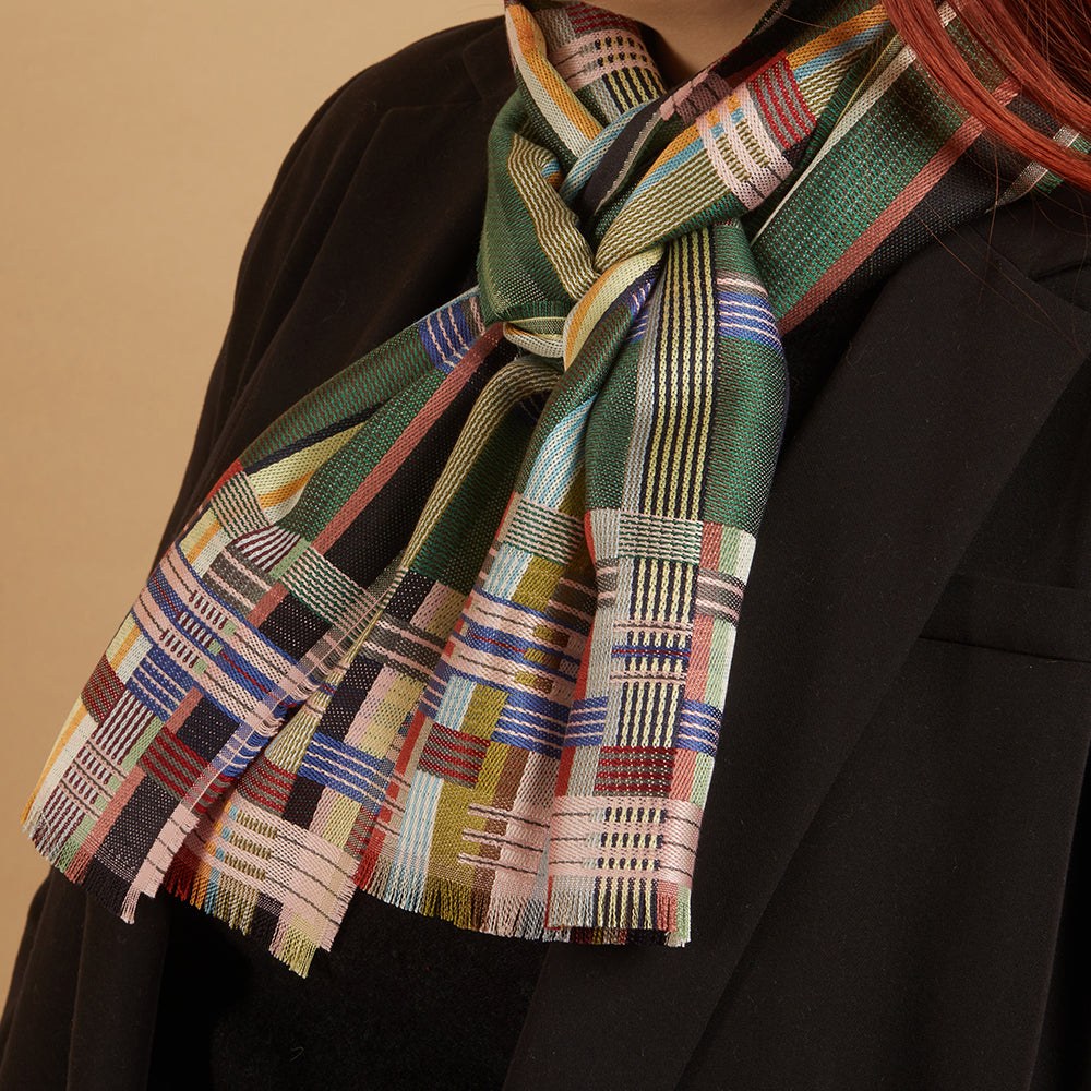 Multicolored plaid scarf draped over a black coat on a beige background