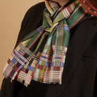 Multicolored plaid scarf draped over a black coat on a beige background