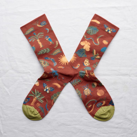 A pair of socks red and orange tones featuring a volcano pattern with animals.