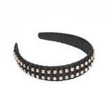 A black headband with fabric ruffles and multiple square silver crystals.