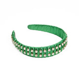 A green headband with fabric ruffles and multiple square silver crystals.